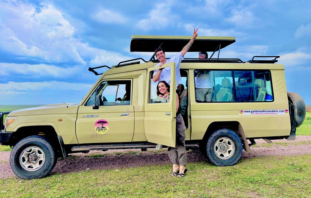 Happy guests with a Gardenia African Safaris pop-top Land Cruiser on the Serengeti plains
